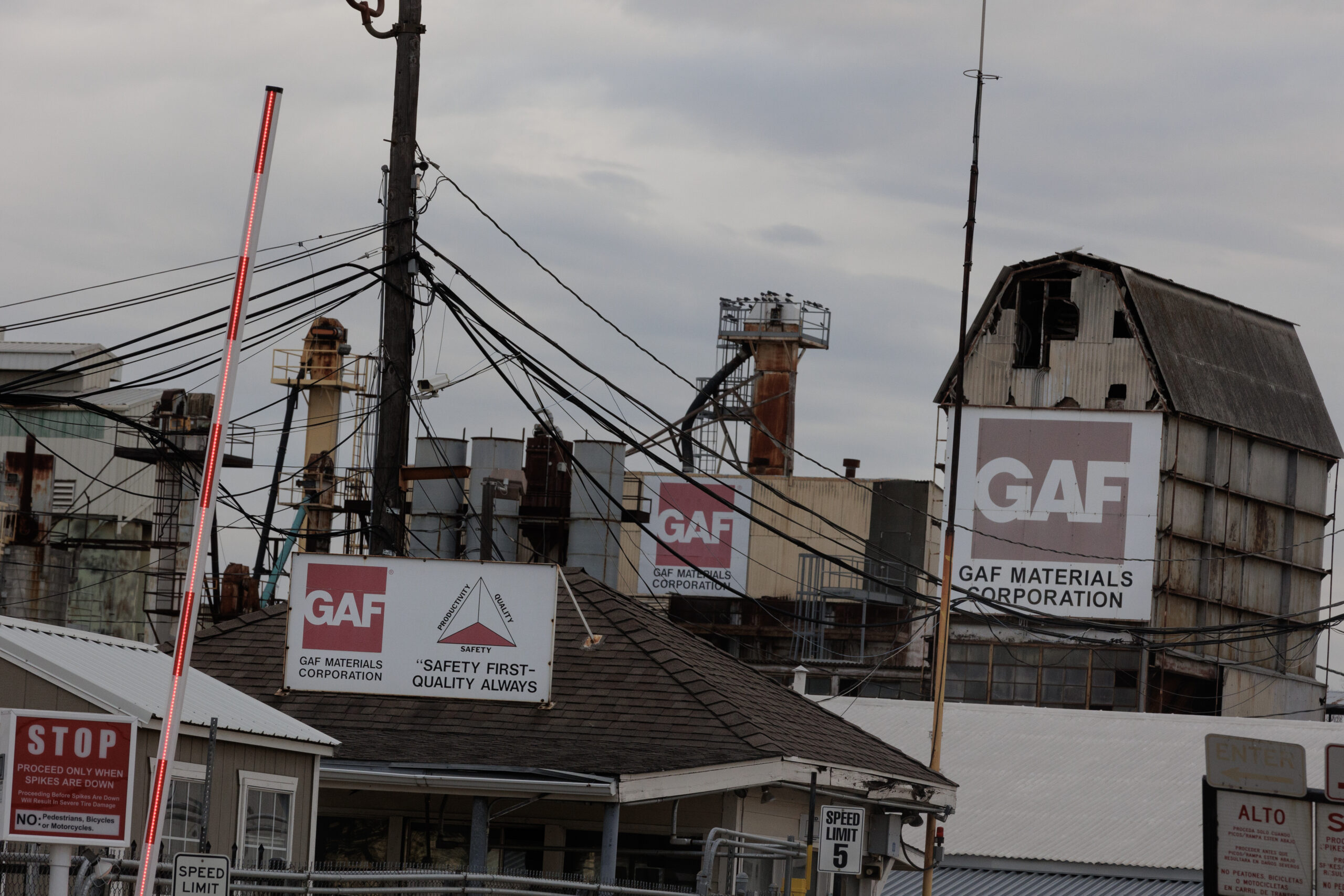 A photo of the GAF roofing and shingle factory, with its own shingled roof, on a cloudy day.