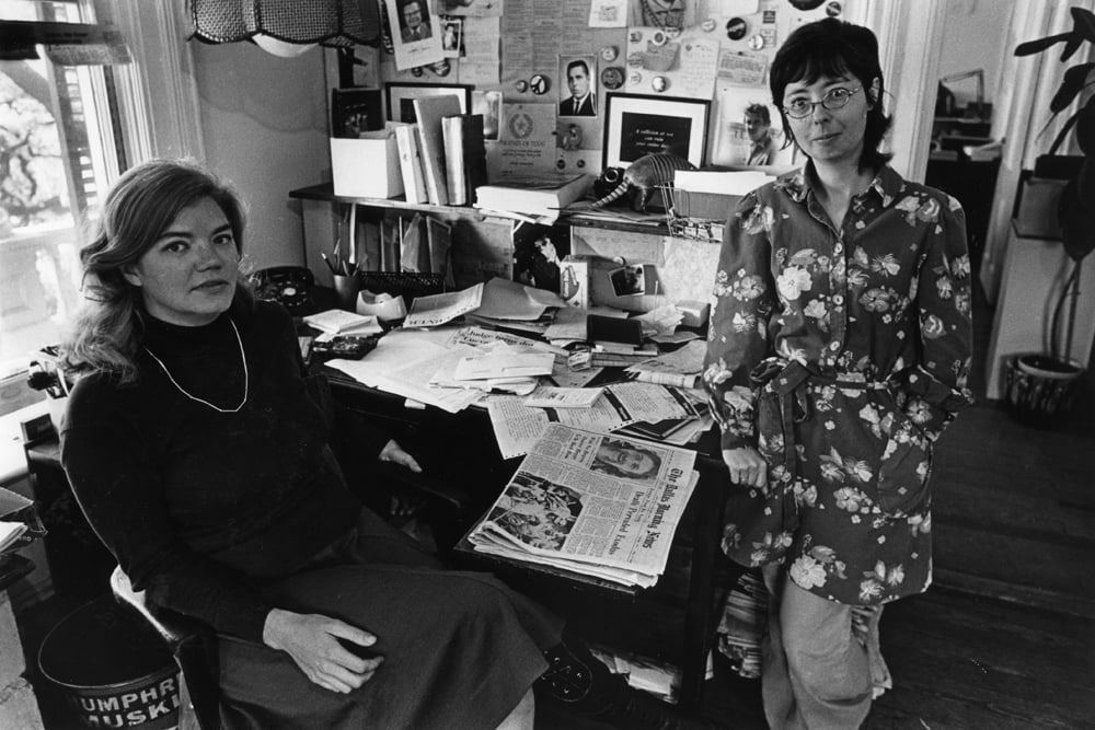 Molly Ivins and Kaye Northcott posing for a photo inside a newsroom.